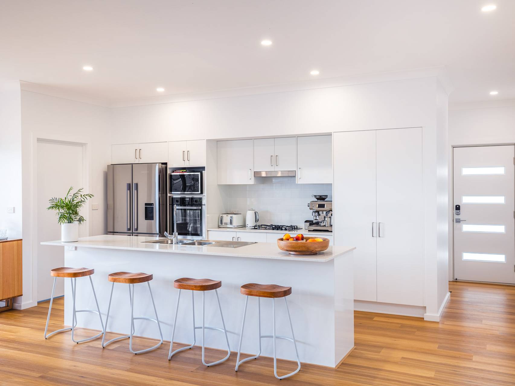 Fresh Modern Kitchen with warm timber floors and an Island Bench opening into the living area