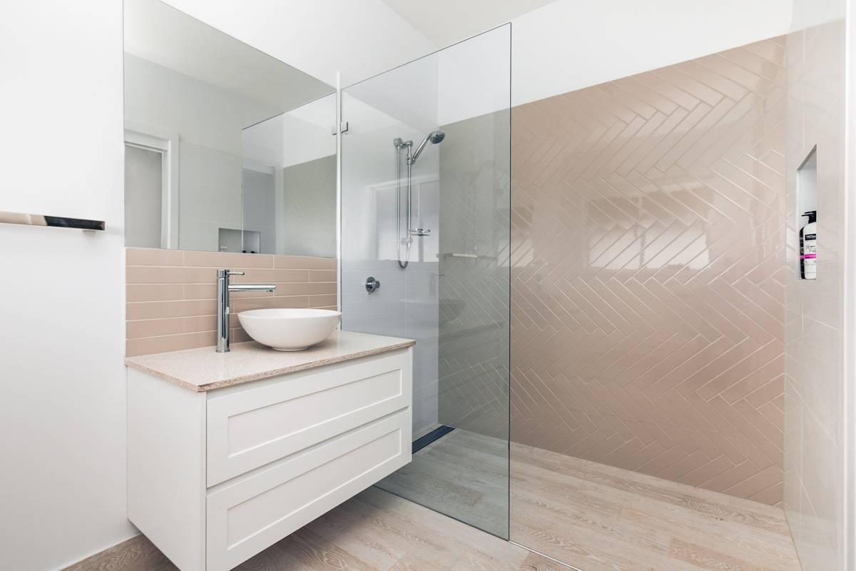 Spacious Bathroom with Herringbone Tiles in shower and modern white freestanding sink and vanity